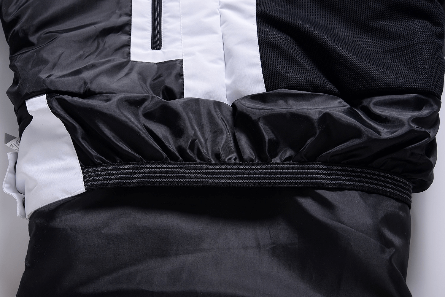 Close-up of a black and white unisex ski jacket with hood, featuring durable materials and stylish details for winter adventures.